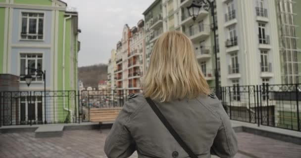 Back view close-up of blond woman in autumn coat standing on city street. Senior Caucasian retiree travelling around the world. Leisure, lifestyle, retirement, happiness. Cinema 4k ProRes HQ. - Кадри, відео