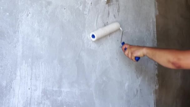 paints the old wall with white paint roller - Materiał filmowy, wideo