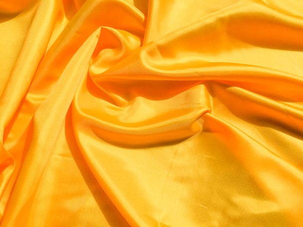Bright yellow silk with waves moving for background. Abstract design with copy space - Foto, imagen