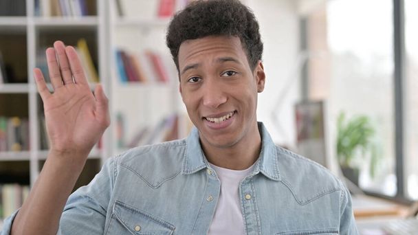 Verrukte jonge Afro-Amerikaanse man zwaaien, zeggen hallo - Foto, afbeelding