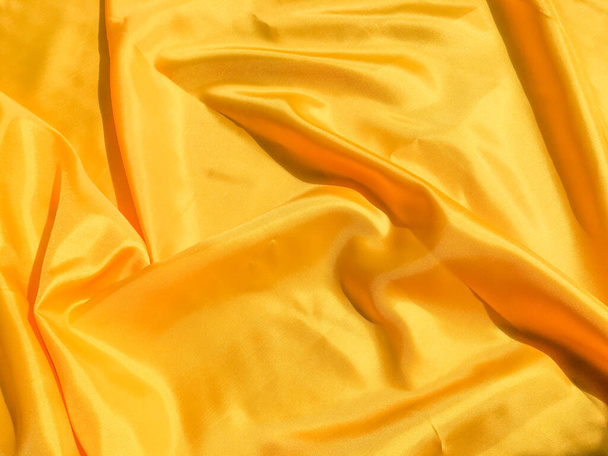 Beautiful yellow silk or satin texture background with copy space for design and artwork  - 写真・画像