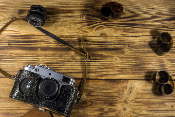 Retro fotocamera met foto film en lens op houten tafel. Bovenaanzicht - Foto, afbeelding