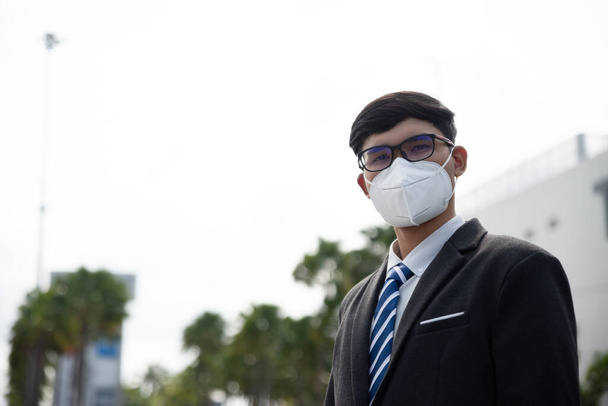 Close up de um homem de negócios em um terno vestindo máscara protetora e tosse, prepare-se para Coronavirus e pm 2.5 lutando contra no fundo da cidade
. - Foto, Imagem