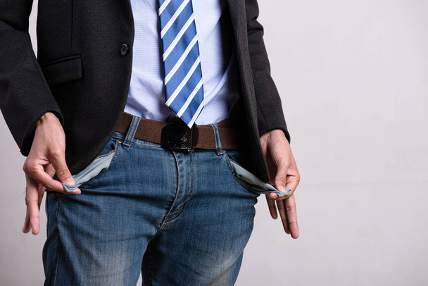 Un giovane uomo d'affari in giacca e cravatta che mostra le tasche vuote. Difficoltà finanziarie, cattiva economia, nessun concetto di denaro
. - Foto, immagini