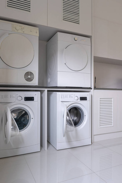 Laundry washing machine and dryer against  modern appliance household in laundry room interior with cabinets - Фото, изображение