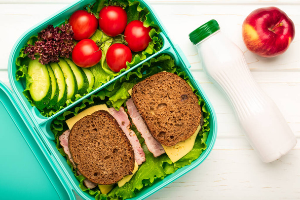 Vista superior da lancheira escolar com sanduíches e legumes e uma garrafa de iogurte: um conceito de nutrição saudável e equilibrada
. - Foto, Imagem