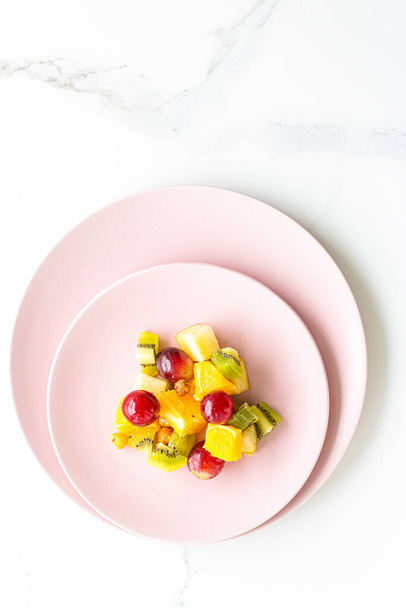 Φρέσκα βιολογικά φρούτα σαλάτα σε ροζ πιάτο, υγιεινή διατροφή και αποτοξίνωση σχέδιο διατροφής, επίπεδη lay - Φωτογραφία, εικόνα