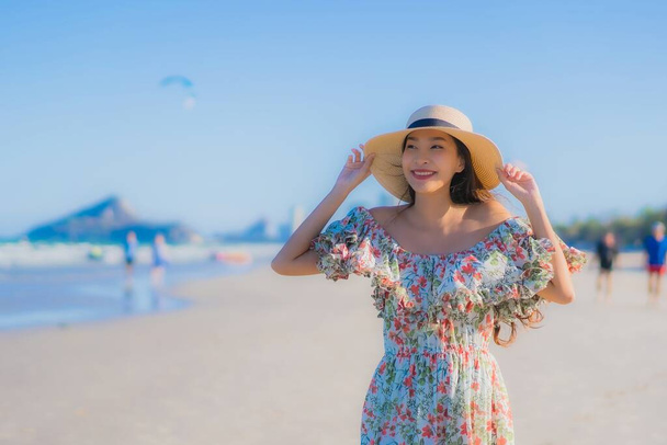 Portret mooie jonge aziatische vrouw gelukkig glimlach ontspannen rond tropische strand zee oceaan op blauwe hemel voor ontspanning - Foto, afbeelding