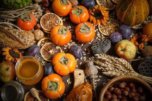 Kürbisse, Kaki, Getreide, Brot, Samen und Nüsse auf hölzernem Hintergrund, Ernte - Foto, Bild