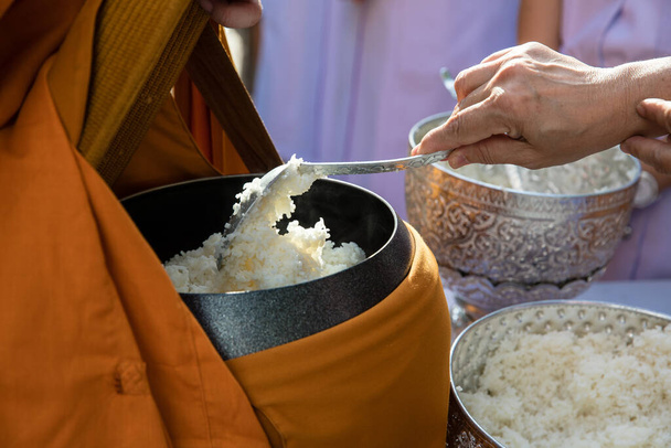 Stará žena ručně dát rýži v almužnu misku buddhistického mnicha na ráno - Fotografie, Obrázek