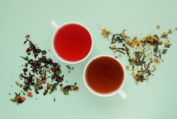 Cups with fruit and herbal tea, dried herbs, healthy drink, herbal medicine, flat lay on green background. - Foto, Bild