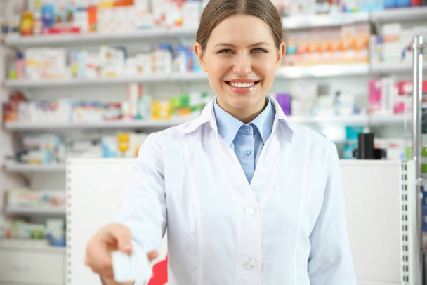 Professional pharmacist with pills in modern drugstore - Foto, afbeelding