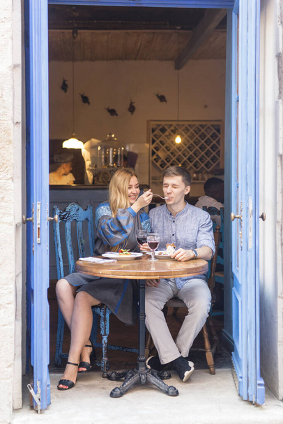 couple in blue clothes having dinner at a restaurant near the blue doors with a view of the city - 写真・画像