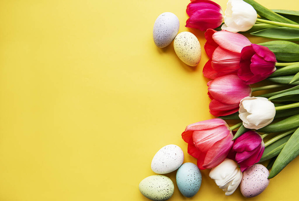 Spring tulips and Easter eggs on a yellow  background - 写真・画像