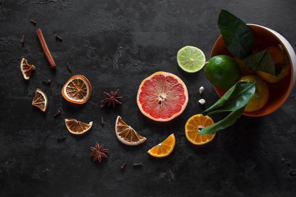 sliced fresh and dry citruses grapefruits, tangerines and lime with cinnamon and star anise on a black background. vitamin c concept - Foto, Imagem