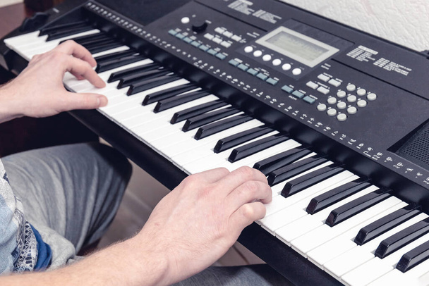 руки піаніста, який грає синтезатор у яскравій домашній студії, вид зверху
 - Фото, зображення