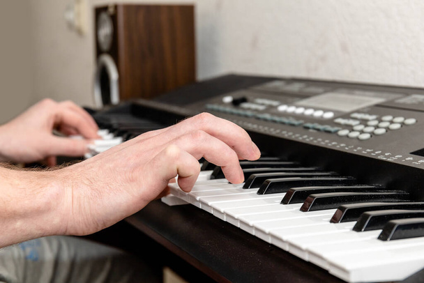 χέρια πιανίστα που παίζει ένα συνθεσάιζερ σε ένα φωτεινό στούντιο στο σπίτι - Φωτογραφία, εικόνα
