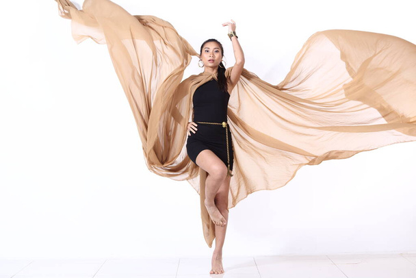 Exotic Woman in Green Short Dress with brown cream chiffon fabric Fluttering in the Air, light see through, studio ligthing white background, jump float moving motion blur concept - 写真・画像