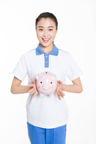 cute chinese girl student holding piggy banks happy smile - Fotó, kép