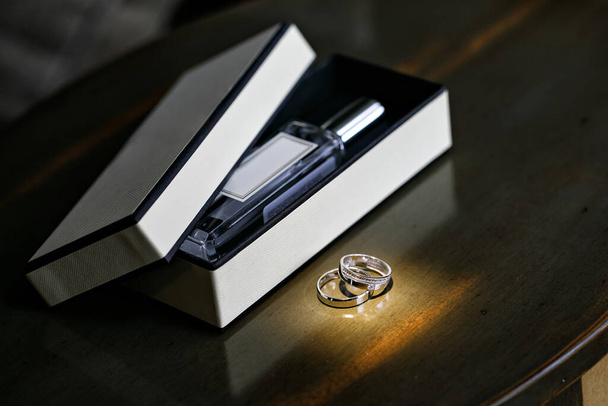wedding rings and a box with a bottle of perfume - Φωτογραφία, εικόνα