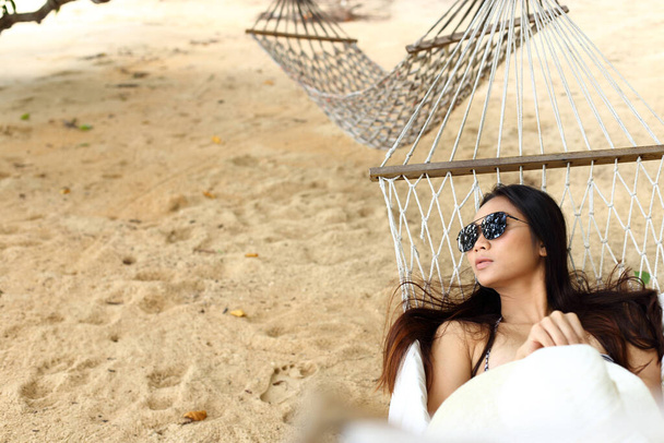 Gebräunte Haut Bikini Mädchen Sonnenbrille liegt auf Hängematte am Strand im Sommerurlaub und wartet auf Liebhaber in einer anderen leeren Hängematte, Kopierplatz für Text-Logo, Konzept Urlaub ruhig allein - Foto, Bild