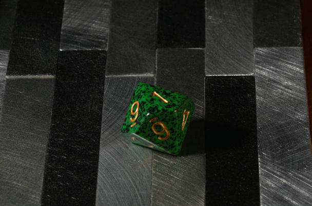 Zelená desetihranná mnohostěná kostka na šedém dlaždicovém stole - Fotografie, Obrázek