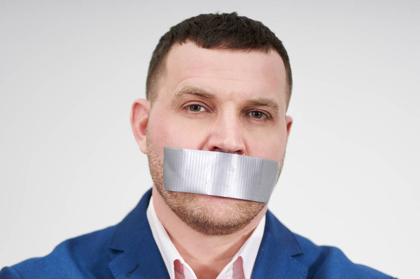 man has a big piece of black industrial tape covering his mouth, silence concept - Photo, Image