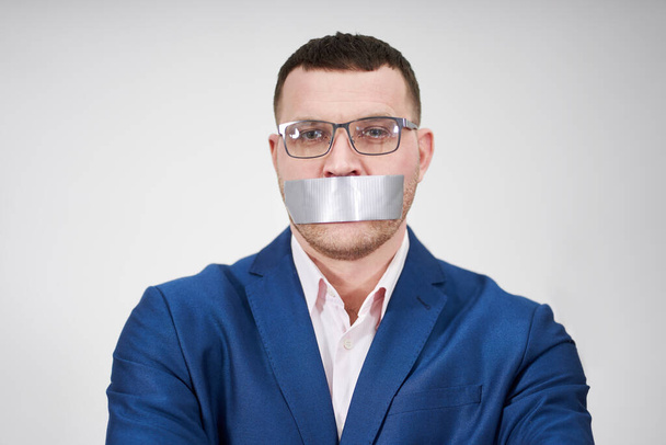 man has a big piece of black industrial tape covering his mouth, silence concept - Foto, Imagen