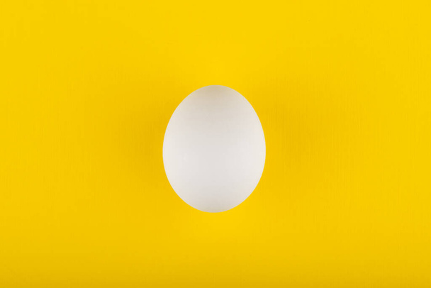 egg on yellow background top view - Foto, Imagem