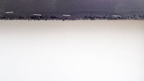 Fondo blanco con una franja de tela negra perforada con grapas a una plancha de madera. Fondo abstracto con espacio de copia
 - Foto, Imagen