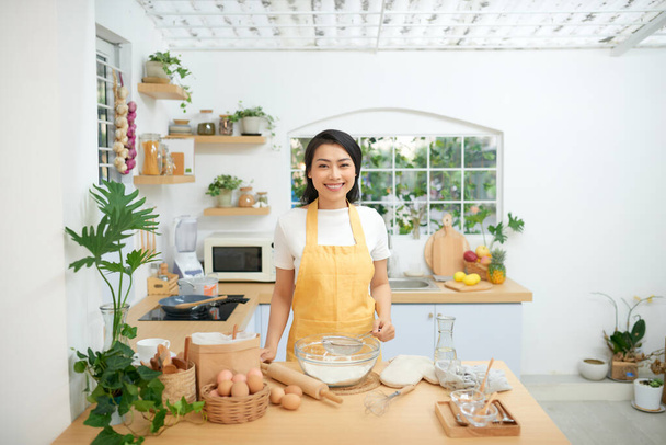Kaunis nuori nainen ruoanlaitto leivonnaiset keittiössä
 - Valokuva, kuva