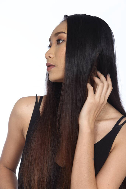 Молода модель моди Жінка довге коричневе чорне пряме волосся виглядає ідеєю і вказує на ліву сторону копіювання простору для текстових оголошень, студія освітлення білий ізольований фон
 - Фото, зображення