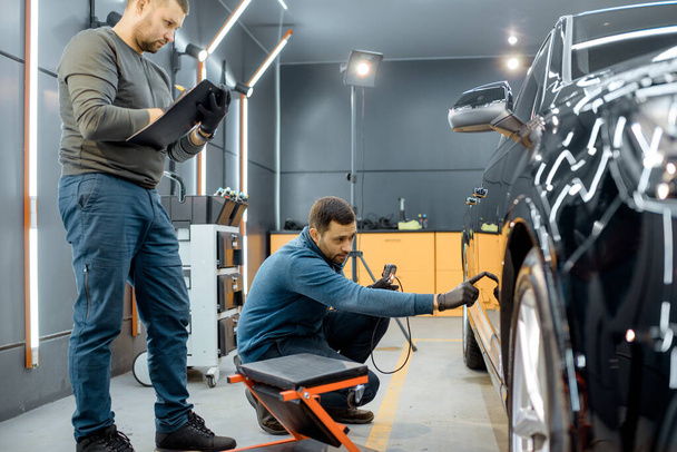 Workers examining vehicle body for scratches - Zdjęcie, obraz