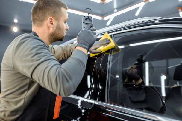 Worker wiping vehicle body with microfiber - Foto, imagen