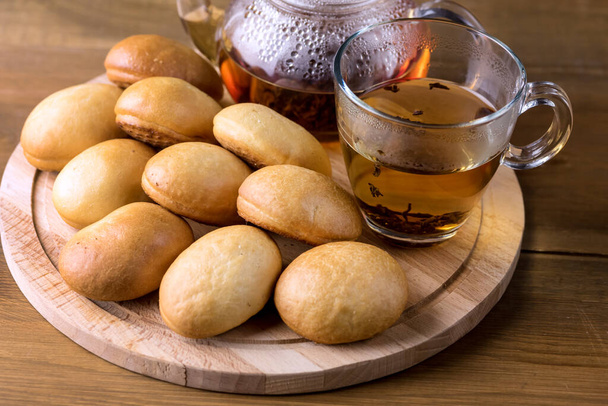 Traditional Small Russian Pies on Wooden Tray Cup of Tea Teapot Wooden Background Horizontal - Φωτογραφία, εικόνα