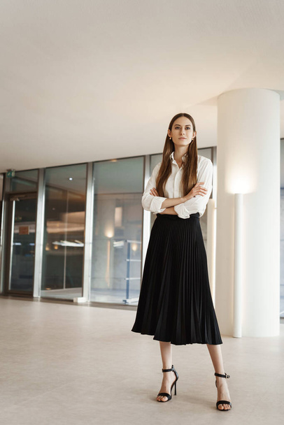 Vertical shot of proud and confident, successful businesswoman in company office, standing assured with crossed hands, looking pleased on distanse as thinking new deals and productive projects - Fotografie, Obrázek