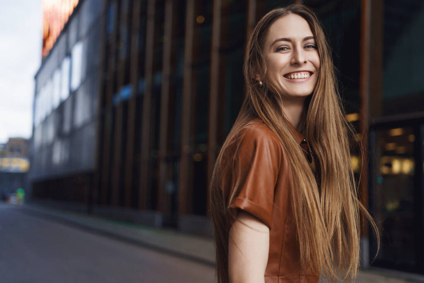 Women career and happiness concept. Gorgeous young woman smiling at camera, turning behind laughing carefree, enjoying beautiful day in favorite city, living her life fullest, standing happy - Valokuva, kuva