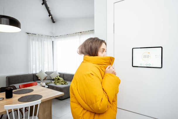 Woman feeling cold, controlling heating with a smart devices at home - Photo, image