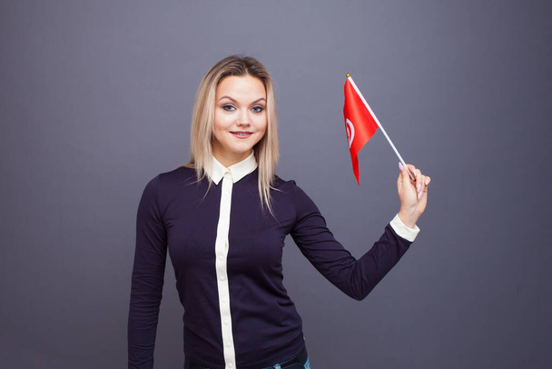 Immigration and the study of foreign languages, concept. A young smiling woman with a Tunisia flag in her hand. - Фото, зображення