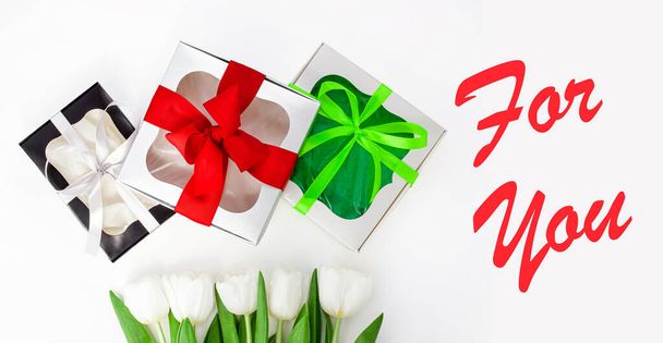 Voor U sms-bericht teken op lichte achtergrond. Witte tulp bloemen en papier geschenkdozen met kleurrijke lint strikken plat lay. Flower Bouquet gefeliciteerd wenskaart. Website banner bovenaanzicht - Foto, afbeelding