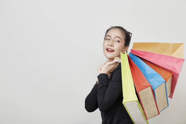 Atraktivní asijské žena úsměv a držení nákupních tašek štěstí černý pátek prodej izolované na bílém pozadí - Fotografie, Obrázek