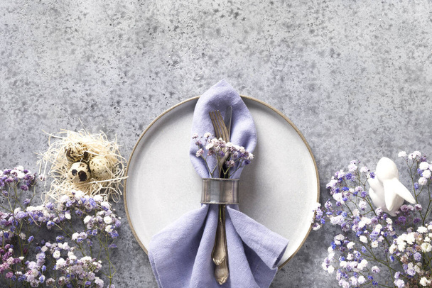 Easter table setting with grey plate and violet decor on grey stone table. Elegance dinner. Top view. Space for text. - Foto, Imagem