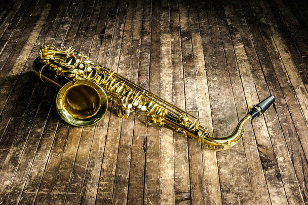 gelbes Jazz-Musikinstrument Saxophon liegt auf einer hölzernen braunen Bühne - Foto, Bild