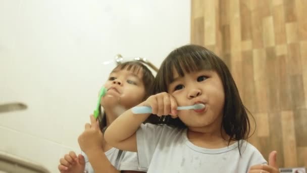 Onnellinen sisarus pieni lapsi tytöt harjaamalla hampaat yhdessä kylpyhuoneessa. Suuhygienian käsite
. - Materiaali, video