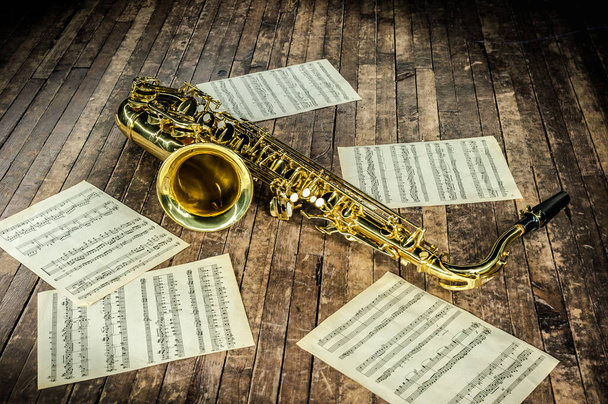 yellow jazz musical instrument saxophone lies on a wooden brown stage - Photo, Image