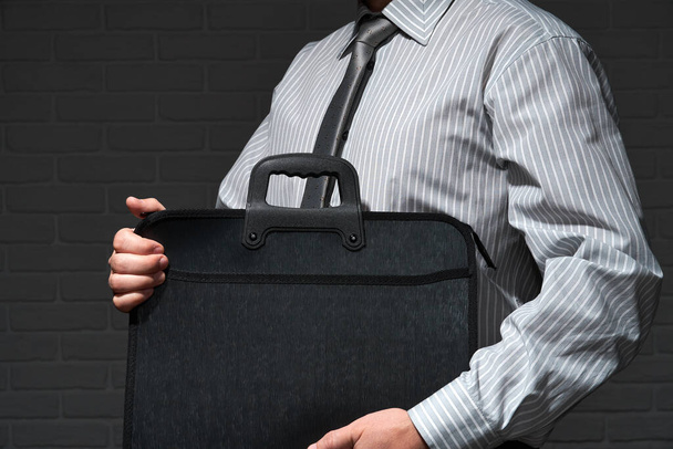 Businessman closeup portrait, he standing and posing with briefcase, dark wall background - Valokuva, kuva