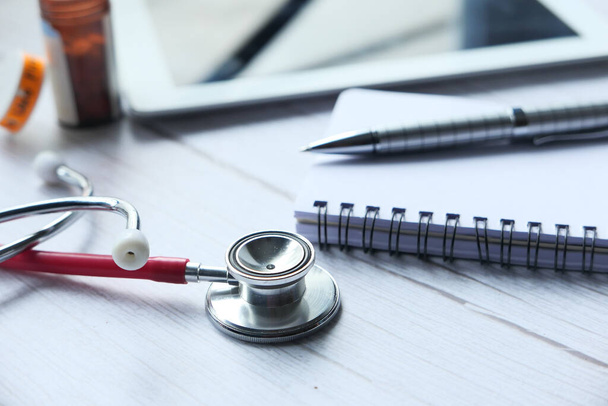 Close up of stethoscope, notepad and pills on table  - Фото, зображення