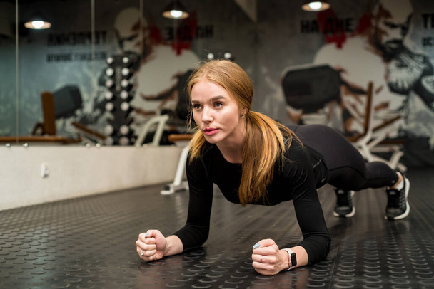 Attrayant jeune femme fait de l'exercice de planche dans la salle de gym - Photo, image