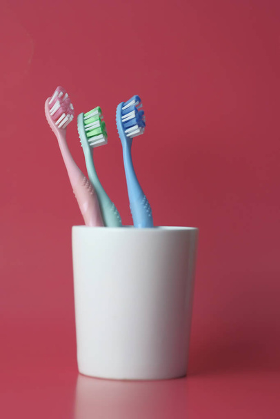 Zahnbürste im Glas auf rotem Hintergrund - Foto, Bild
