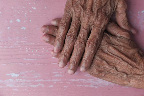 Крупный план рук пожилых женщин, сложенных на столе
 - Фото, изображение